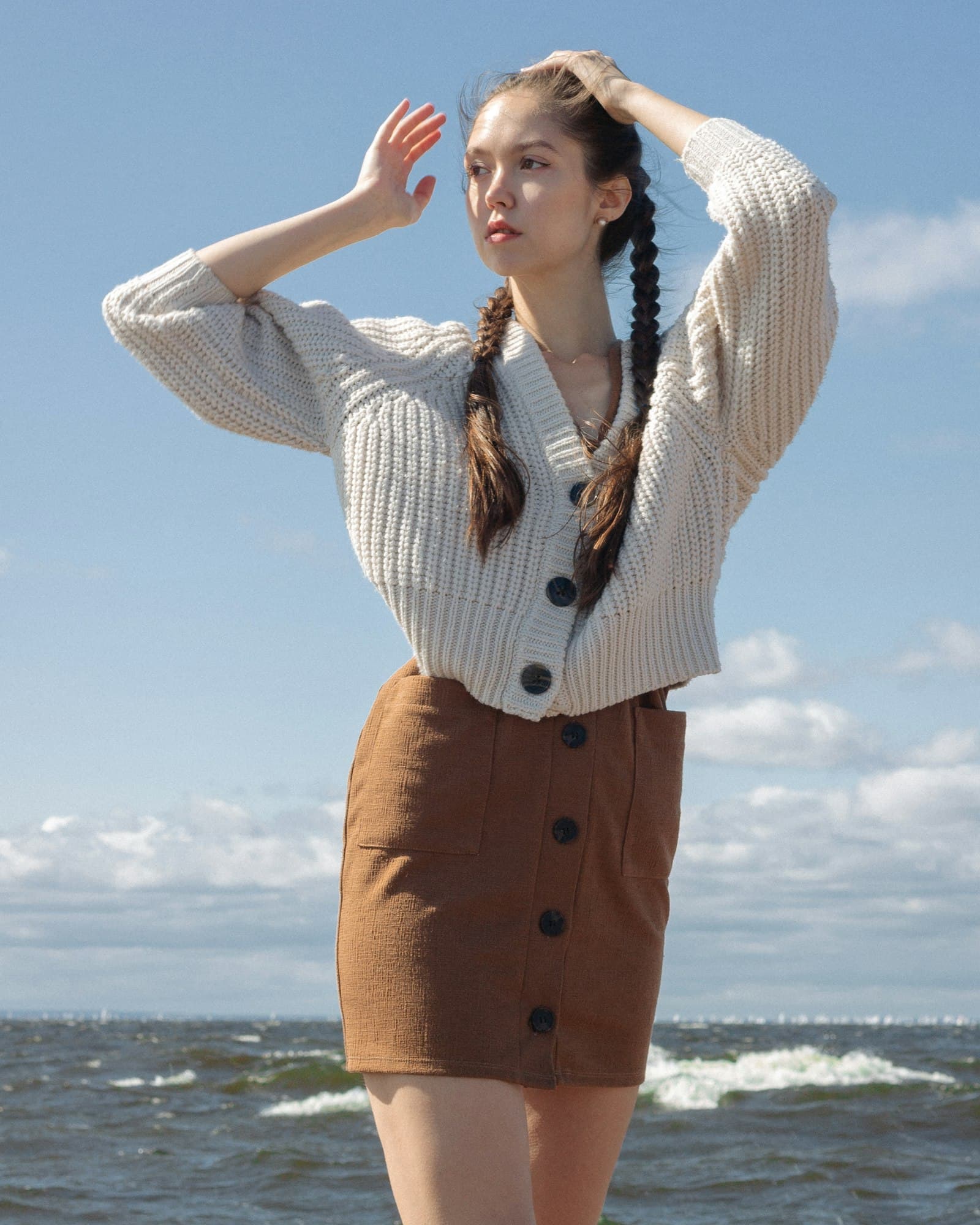Woman in white and black striped long sleeve shirt and brown skirt standing on beach during