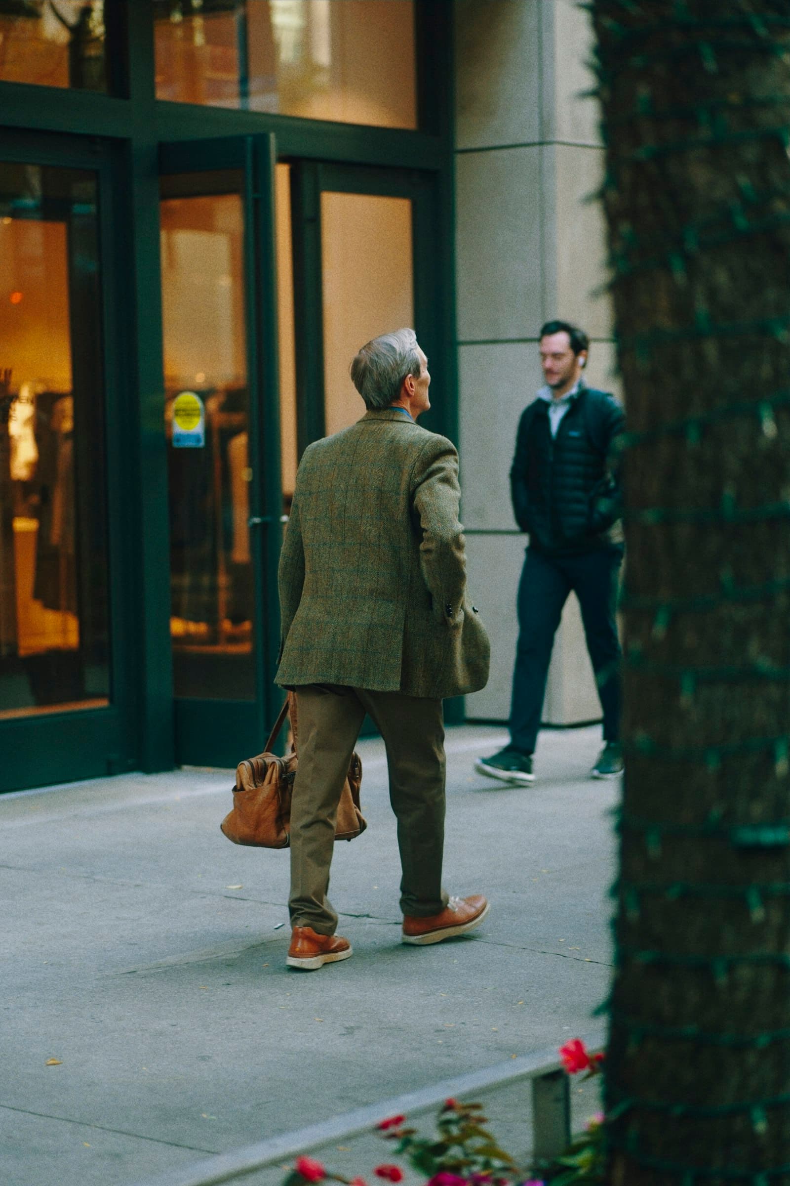 Man in tweed jacket walks past store entrance