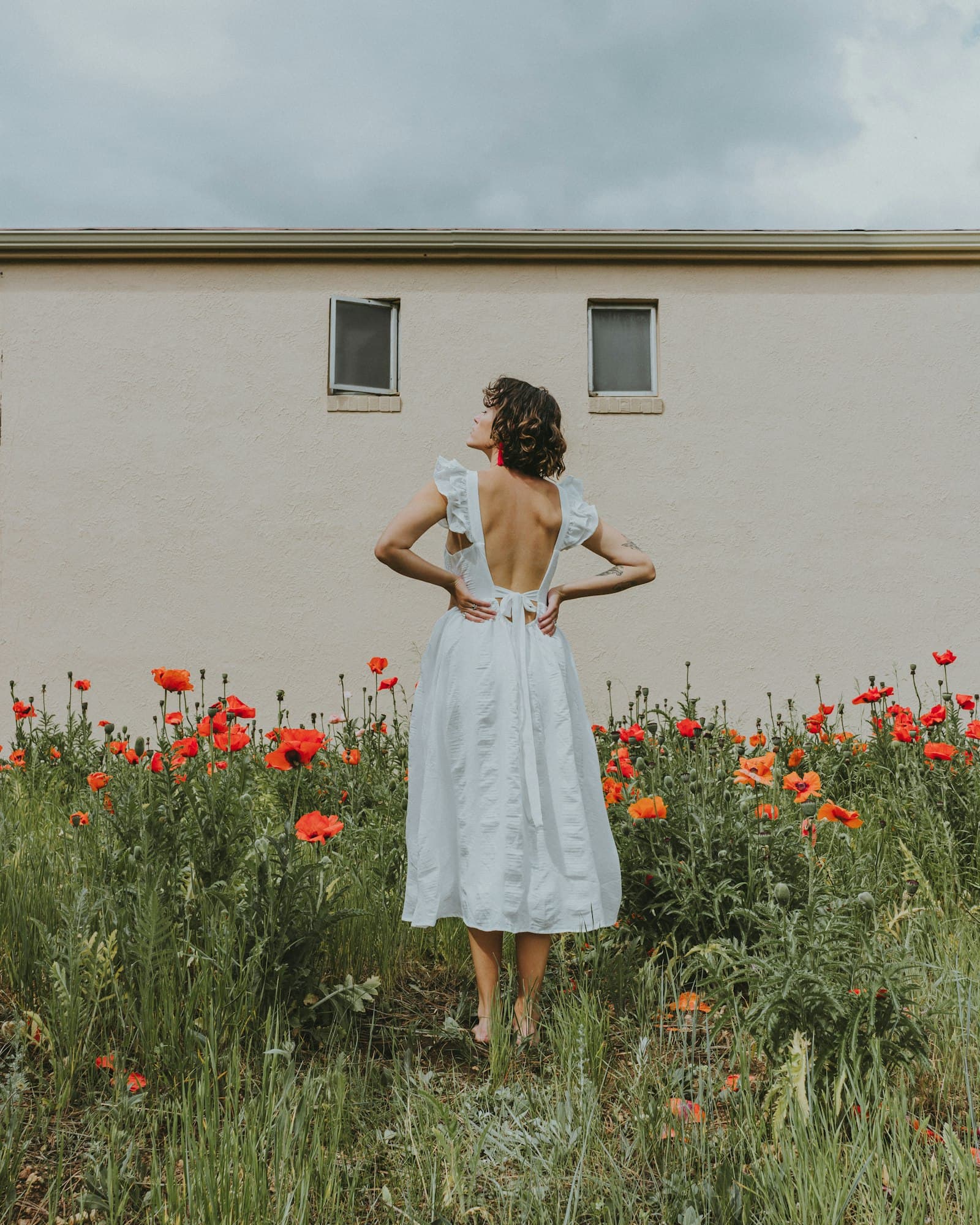 Woman in white dress standing on red flower field during daytime