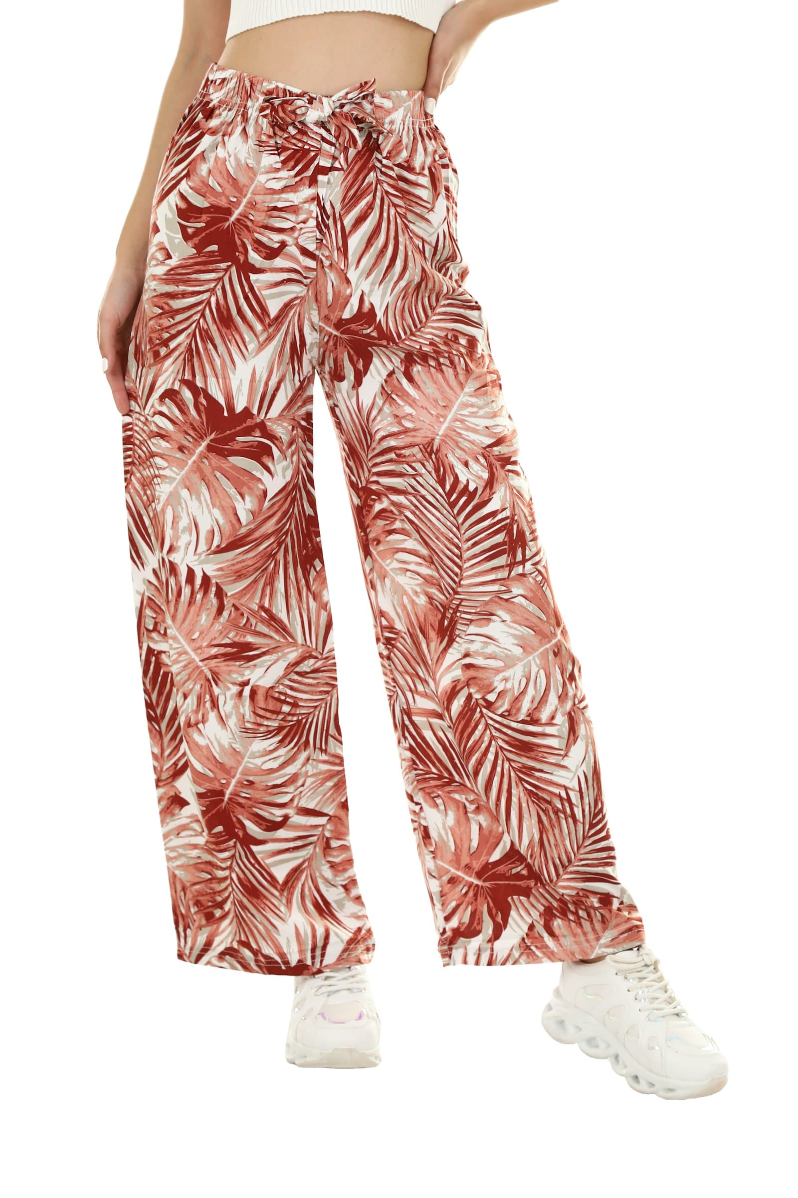 A person wearing wide-leg trousers with a red and white palm leaf print