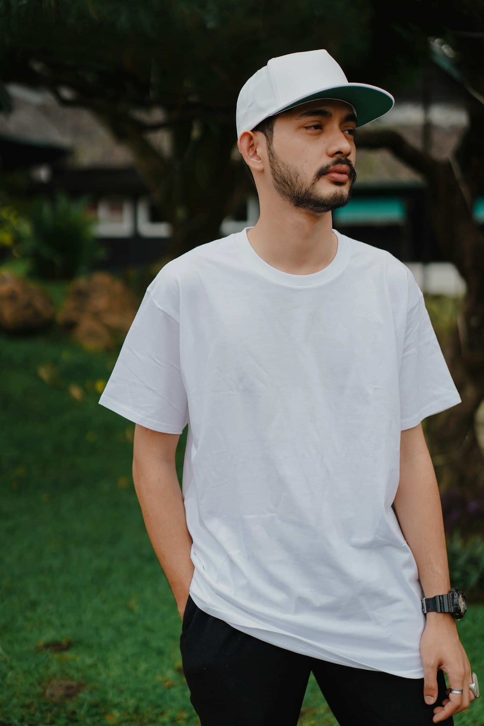 Man in white crew neck t-shirt standing on green grass field during daytime